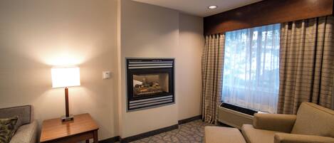 Habitación de hotel con sofá, sillón, una mesita y chimenea.