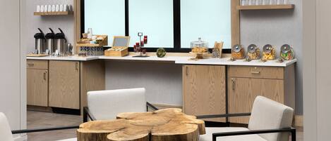 A modern kitchen with a wooden island, white chairs, and a large window.
