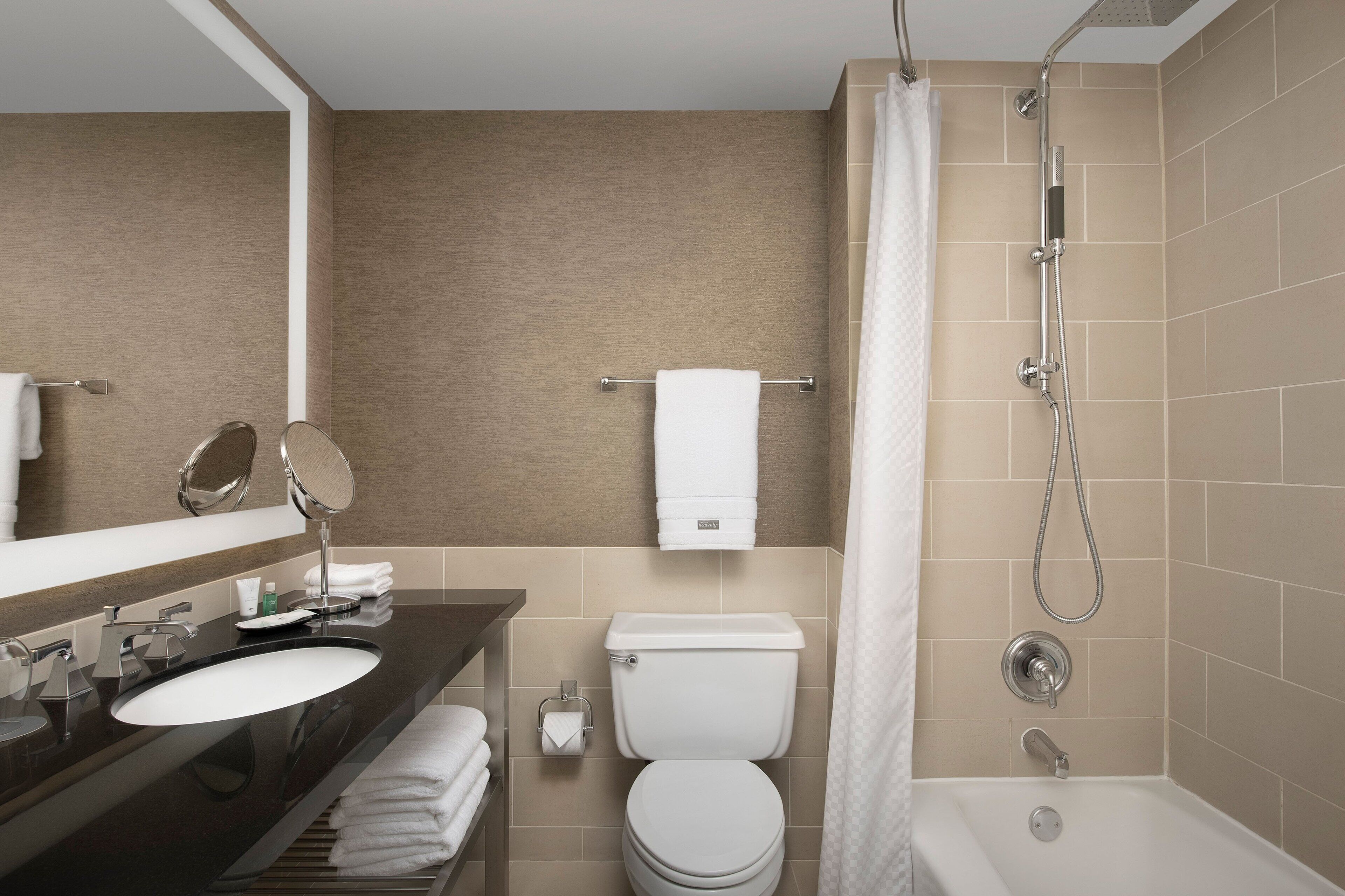 A modern bathroom with a dark countertop sink, a toilet, and a shower area.