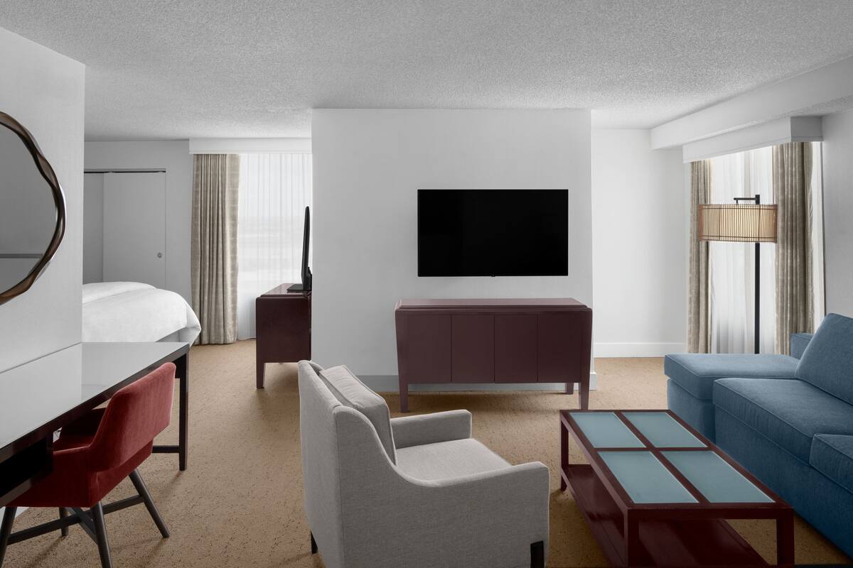Une chambre d’hôtel moderne équipée d’un lit, d’un bureau, d’une télévision, d’un canapé et d’une table basse.
