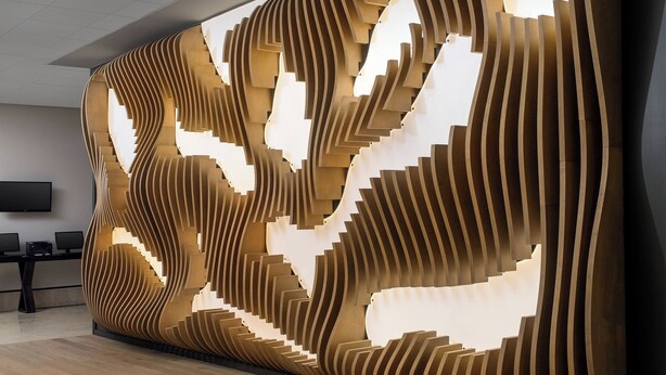 Un espace d’accueil moderne doté d’un décor mural en bois original et d’un téléviseur à écran plat fixé au mur.