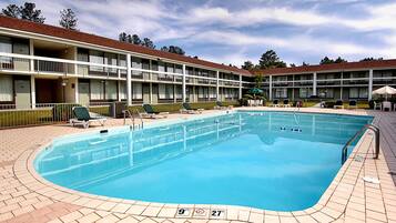 Relax by the rectangular pool surrounded by lounge chairs and umbrellas.