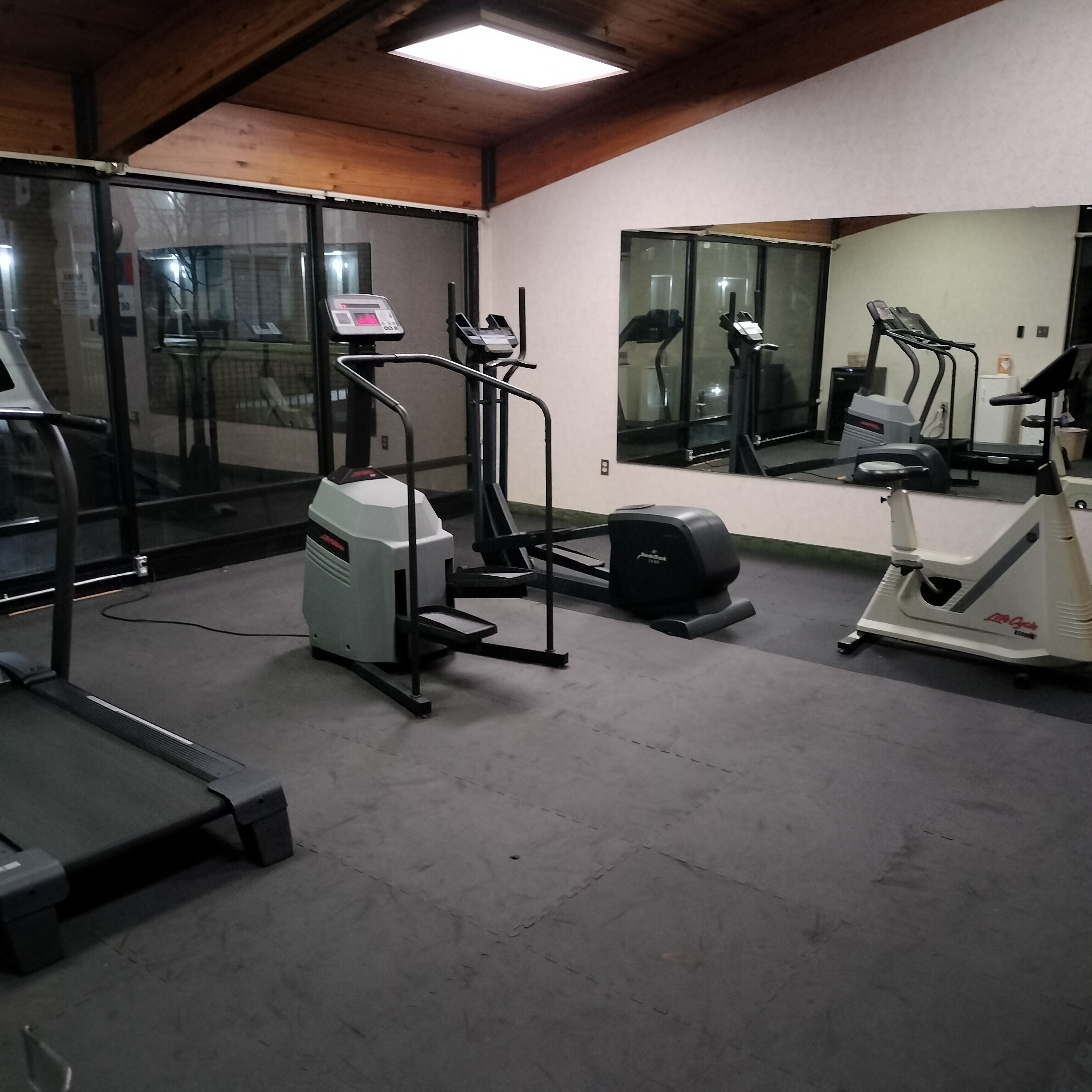 A gym with exercise equipment, a large mirror, and a concrete floor.