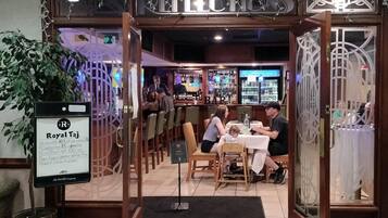 A restaurant with a bar area, a menu board, and a seating arrangement for guests.