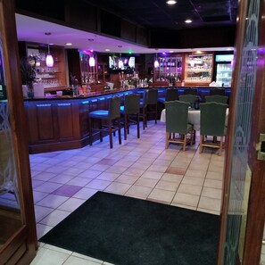 A bar area with a counter, bar stools, and a tiled floor. - Clarion Inn Southern Pines - Pinehurst (Southern Pines)