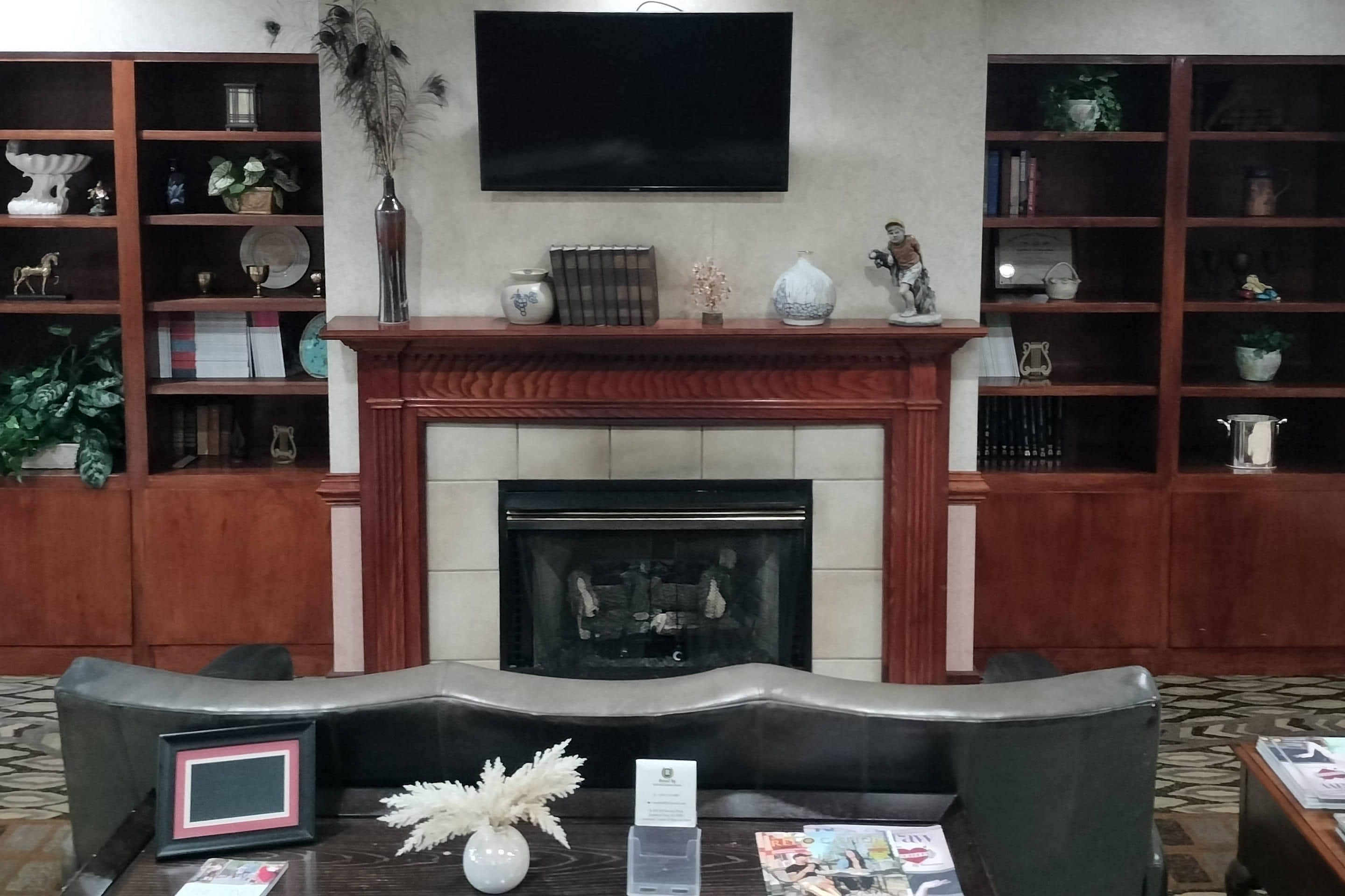 A living room with a fireplace, a television mounted on the wall, and bookshelves filled with decorative items.