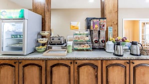 Une petite cuisine équipée d’un réfrigérateur, d’un grille-pain, d’une machine à café et de divers produits alimentaires.