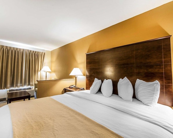 Habitación de hotel con una cama grande, dos lámparas de noche, un cabecero de madera y un escritorio con teléfono.