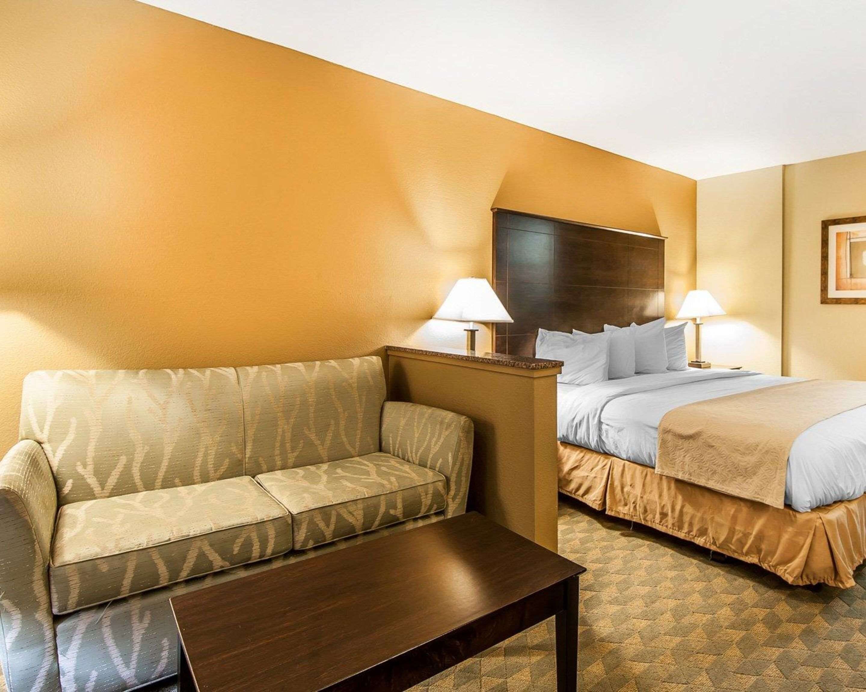 A hotel room with a sofa, a bed, a nightstand, and a table.