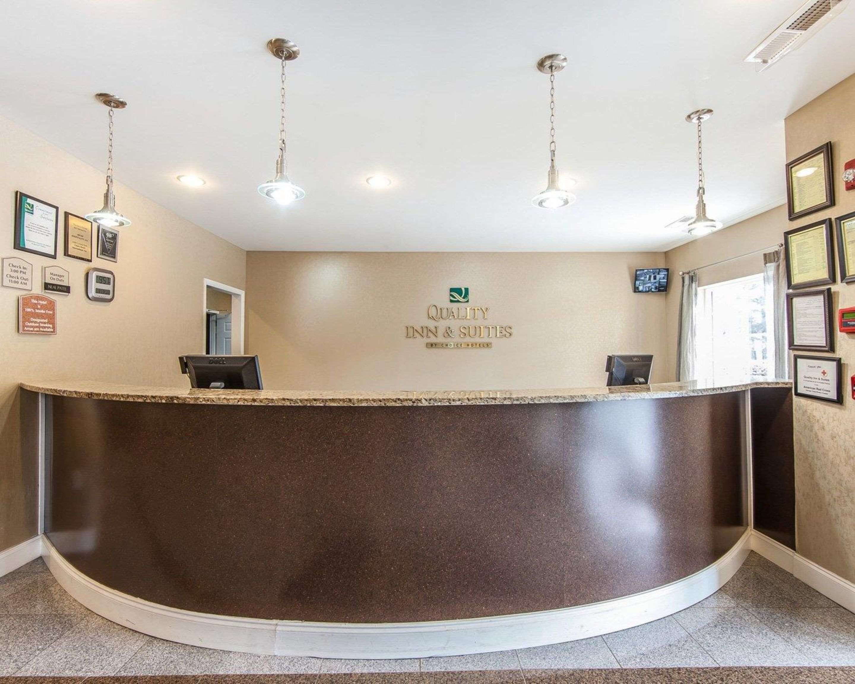 A reception desk with a sign reading "Quality Inn & Suites" and a clock above it.