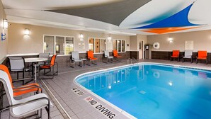 An indoor swimming pool with a 'NO DIVING' sign, lounge chairs, and a pool area use sign.