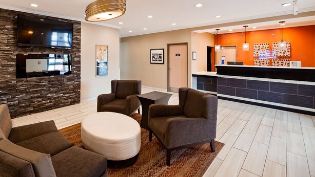 A modern lobby with a stone accent wall, comfortable seating, a reception desk, and a flat-screen TV.