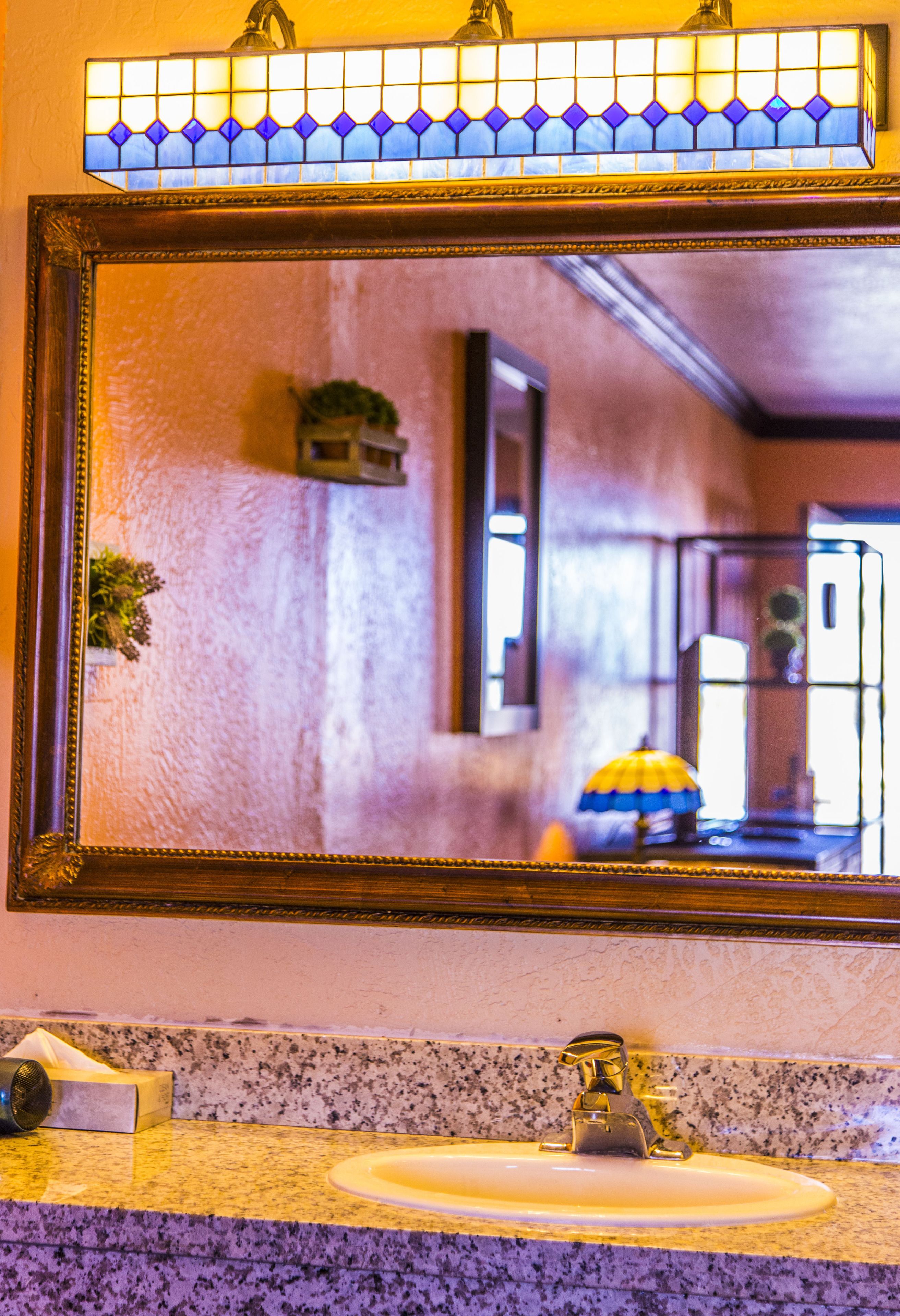 A bathroom with a large mirror, a sink, and a towel dispenser.