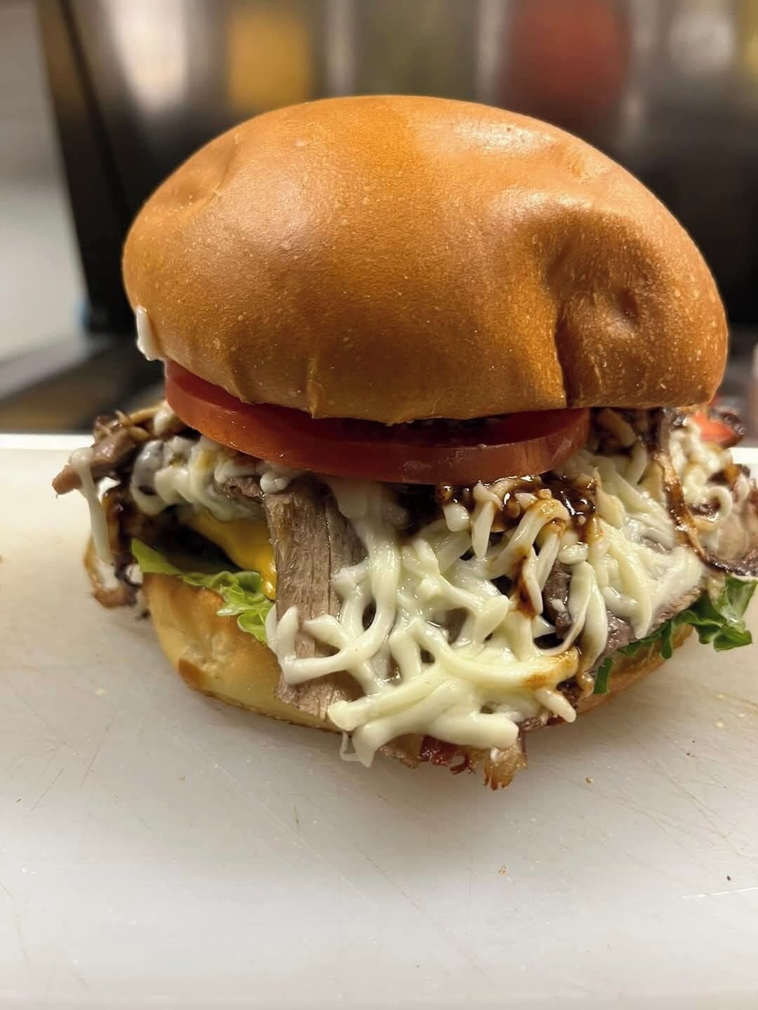 Un sándwich con pan, carne, queso, lechuga y tomate.