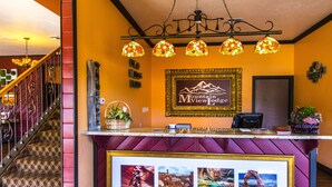 A reception desk with a framed logo, a staircase, and a chandelier. - Mountain View Lodge (Parowan)