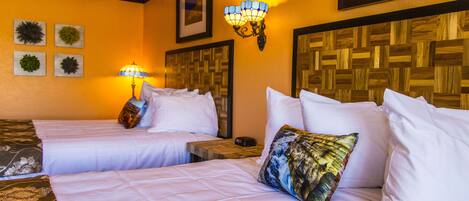 Habitación de hotel con dos camas, cabecero de madera, lámpara de pared y cuadros enmarcados.