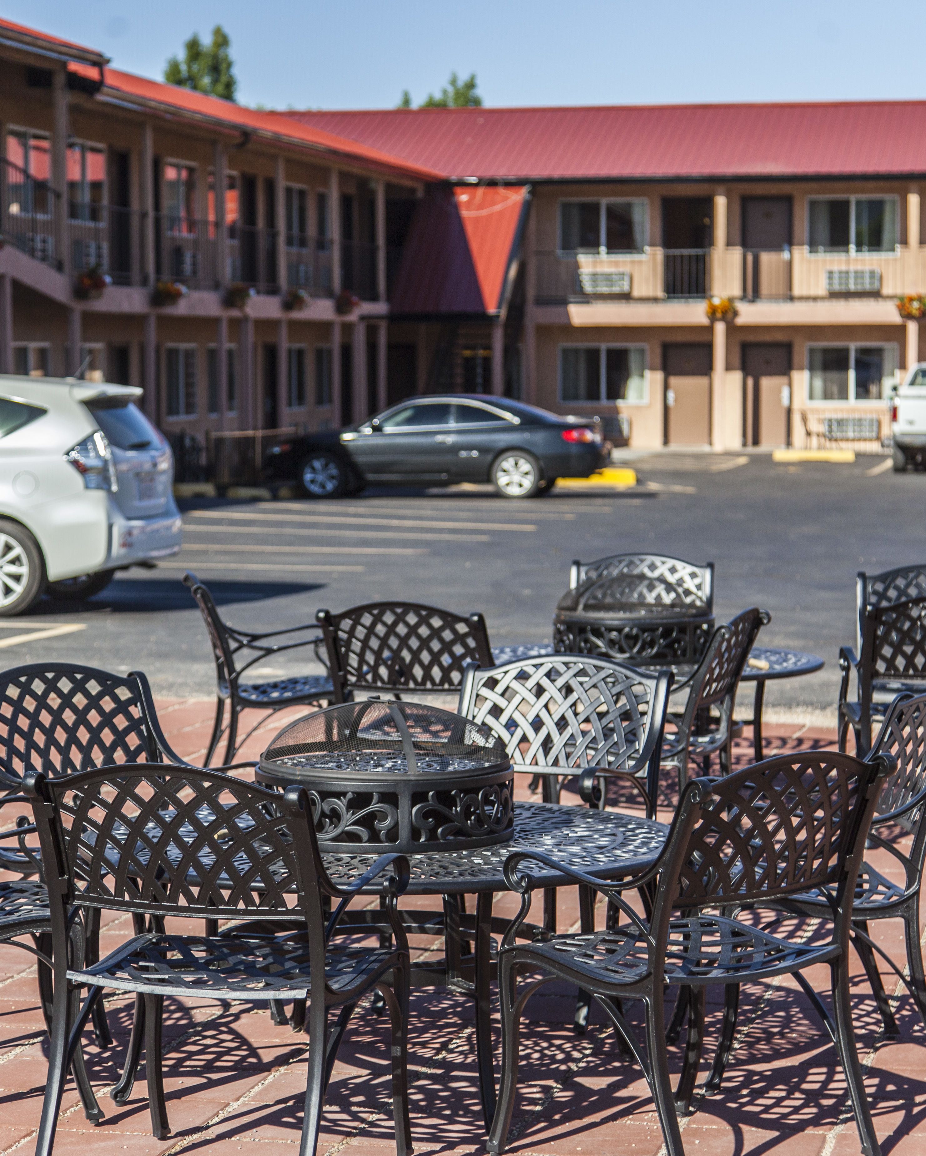 Outdoor metal chairs and tables arranged on a patio with a building in the background.