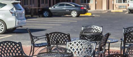 Outdoor metal chairs and tables arranged on a patio with a building in the background.
