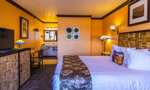 Relax in a spacious room with a large bed, desk, and TV, surrounded by framed artwork and a window with an outside view.