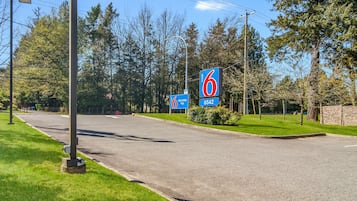 A road with a motel sign, a welcome sign, and a street lamp.