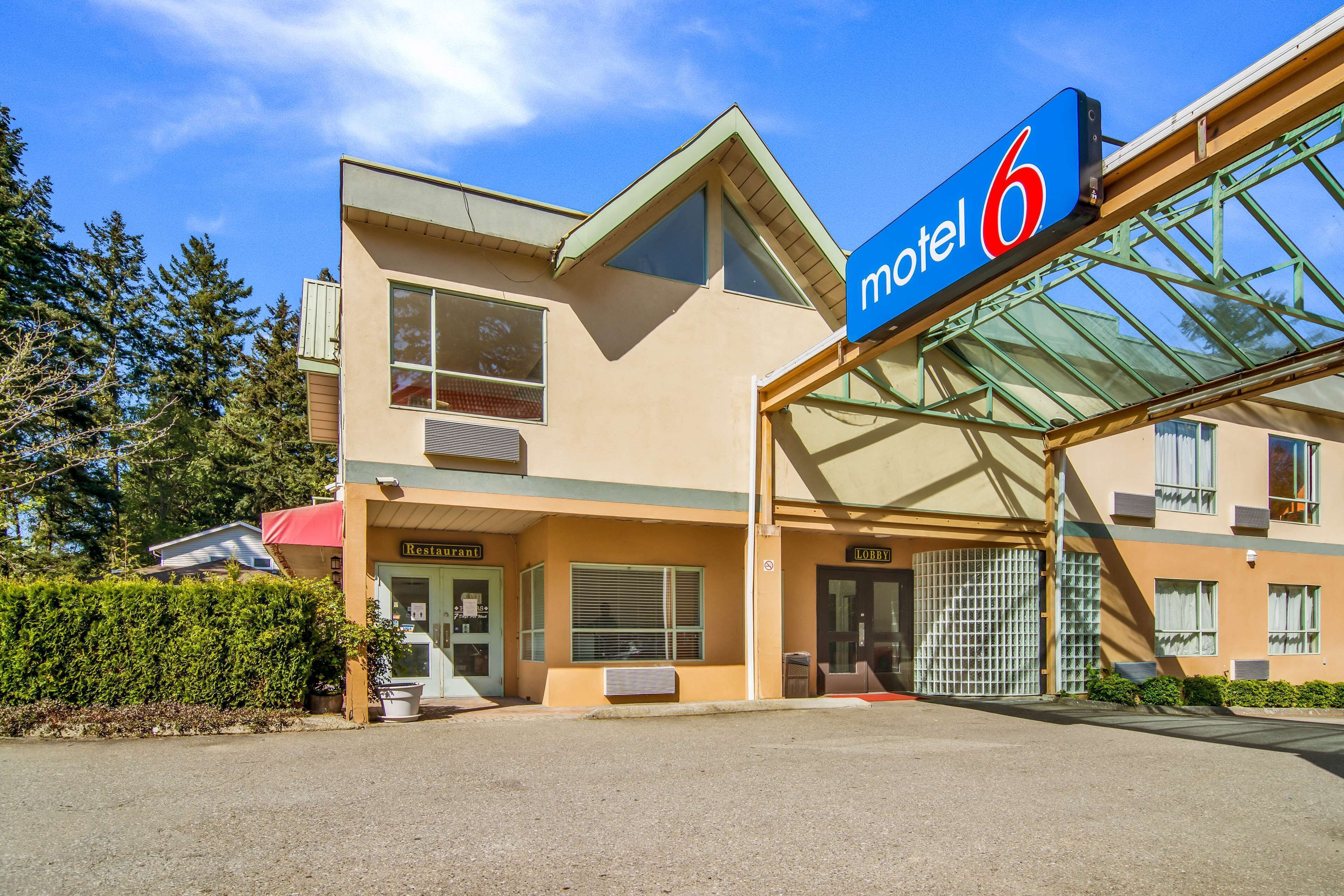 Ein Motel mit einem gut sichtbaren 'Motel 6'-Schild, einem Restaurant und einem Empfangsbereich.