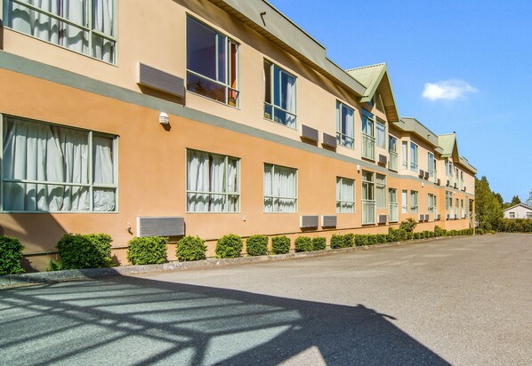 A multi-story hotel with a flat roof, large windows, and a paved driveway. - Motel 6 Surrey, BC (Surrey)
