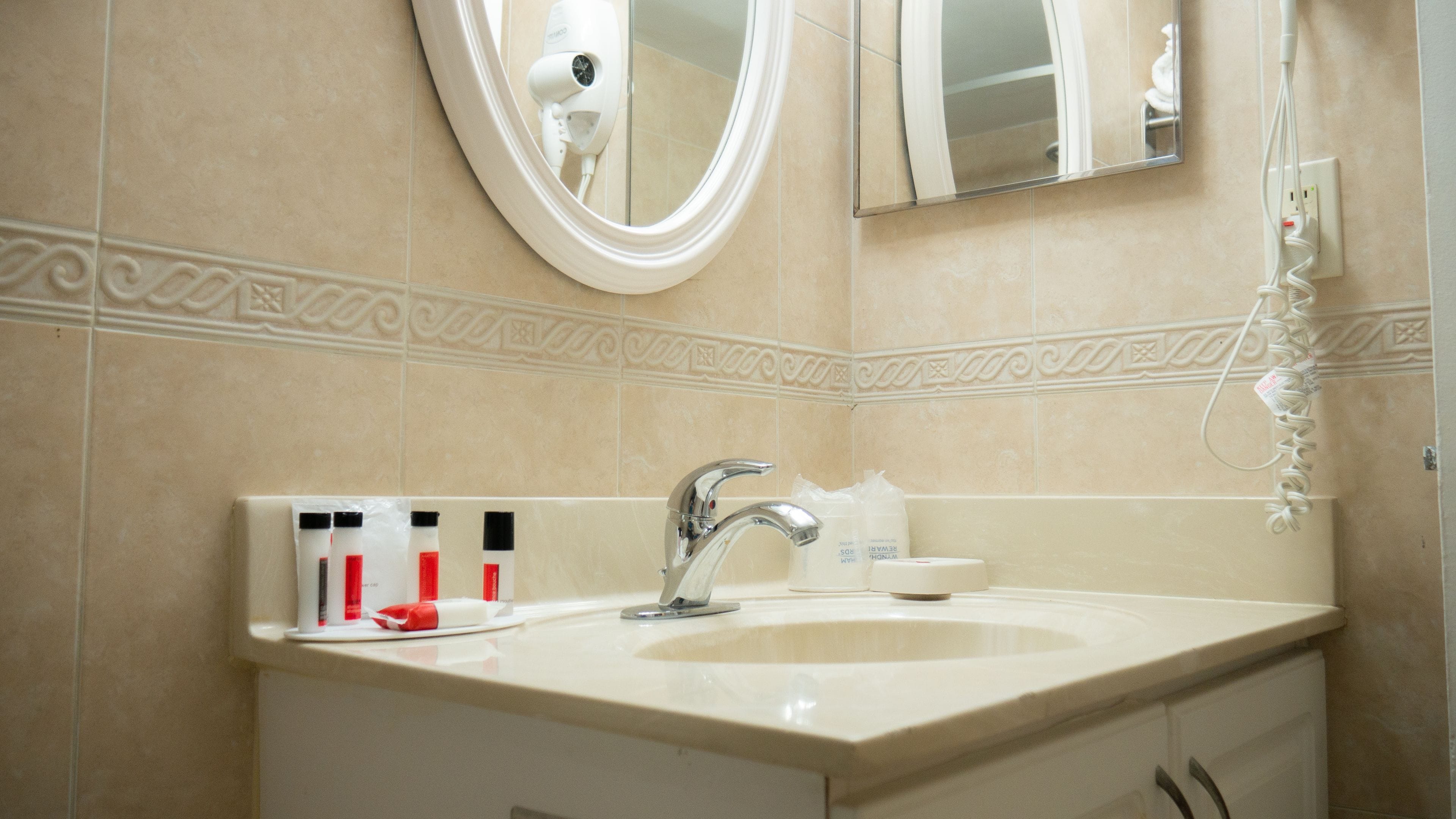 Un baño con lavamanos, espejo y artículos de aseo.