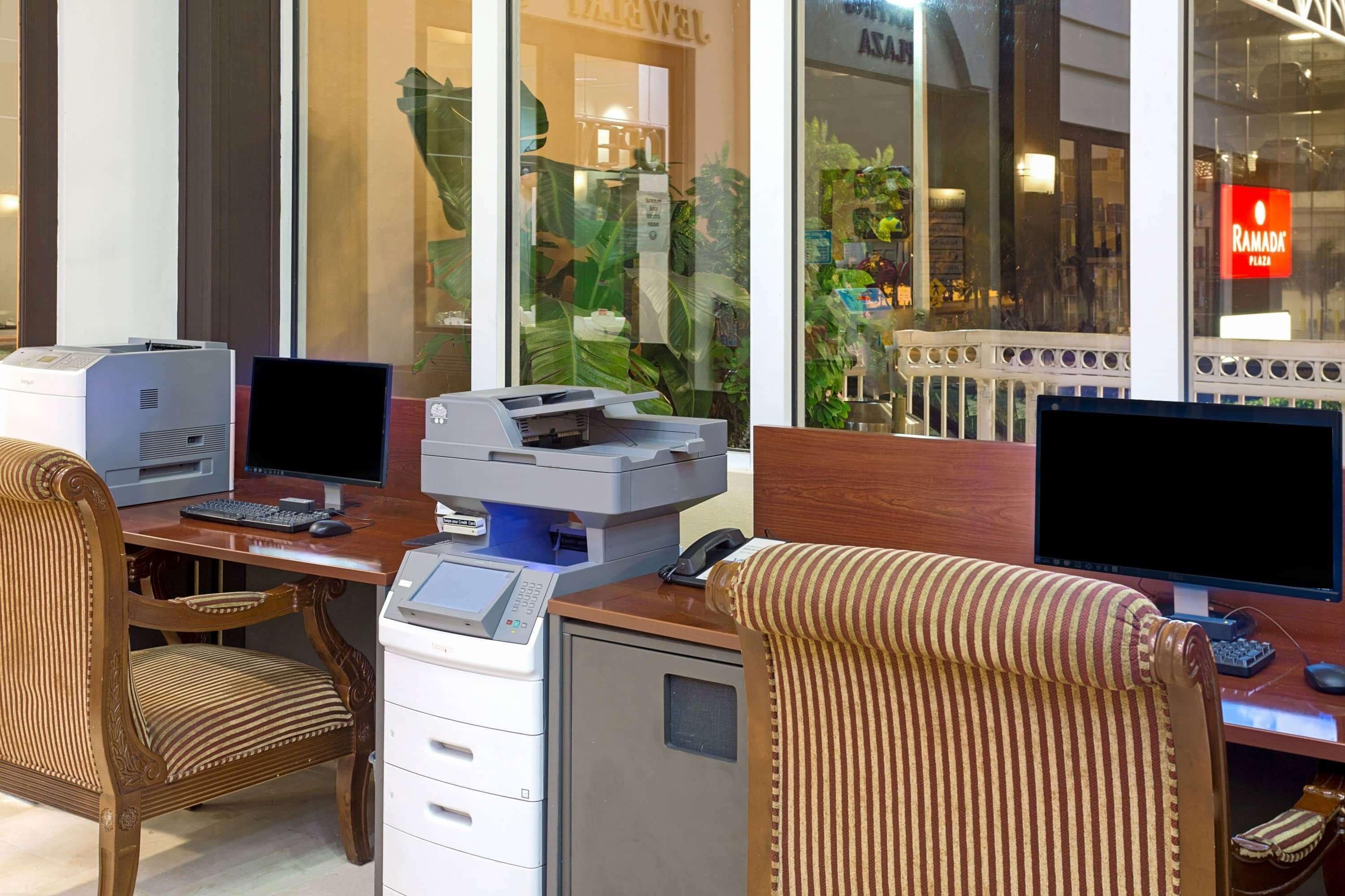 Un espace de travail équipé de deux ordinateurs de bureau, d’une imprimante et d’un classeur.