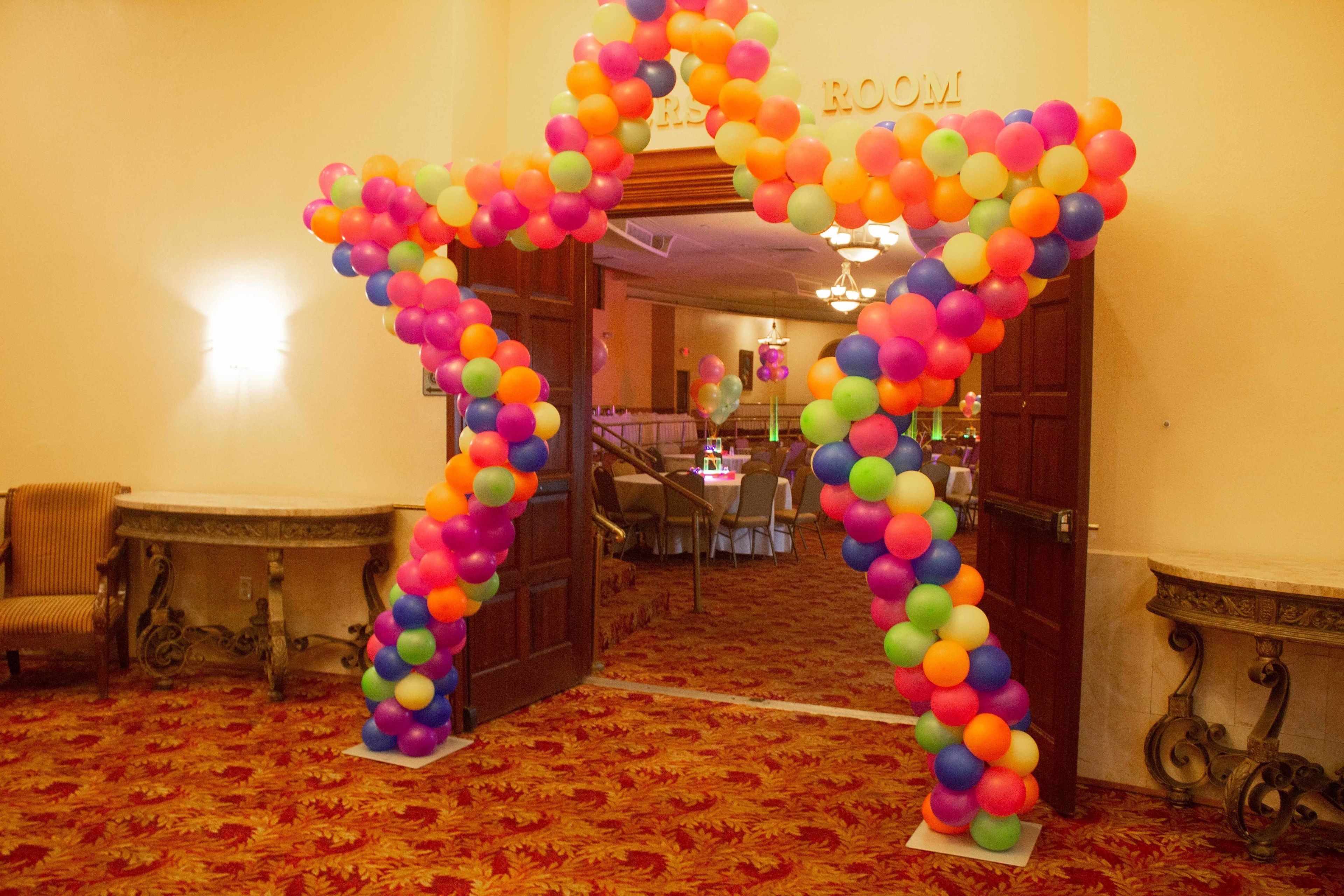 A room with a colorful balloon archway leading to a reception area.
