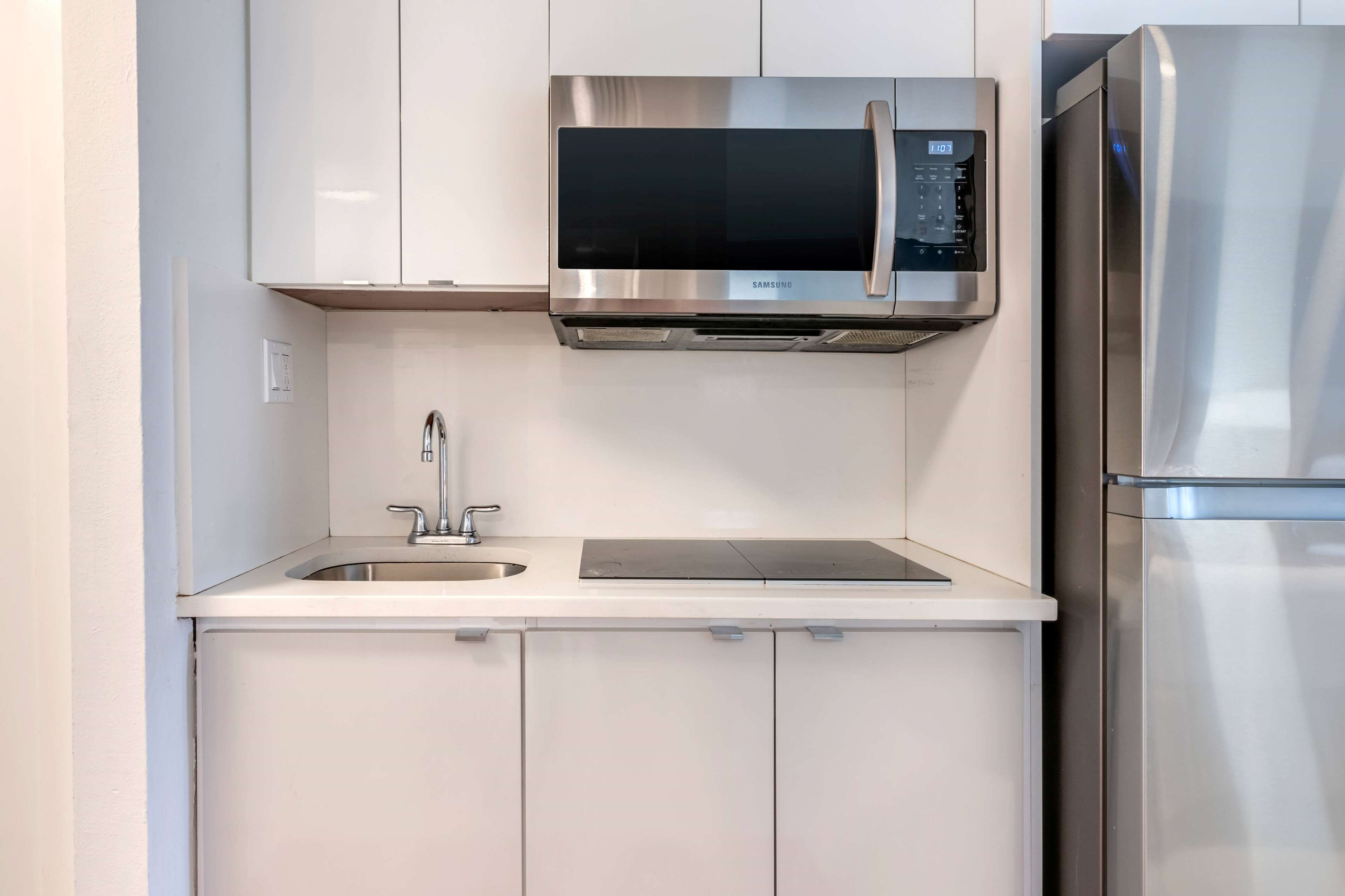 Eine moderne Küche mit Mikrowelle aus Edelstahl, einem Backofen und einem Kühlschrank.