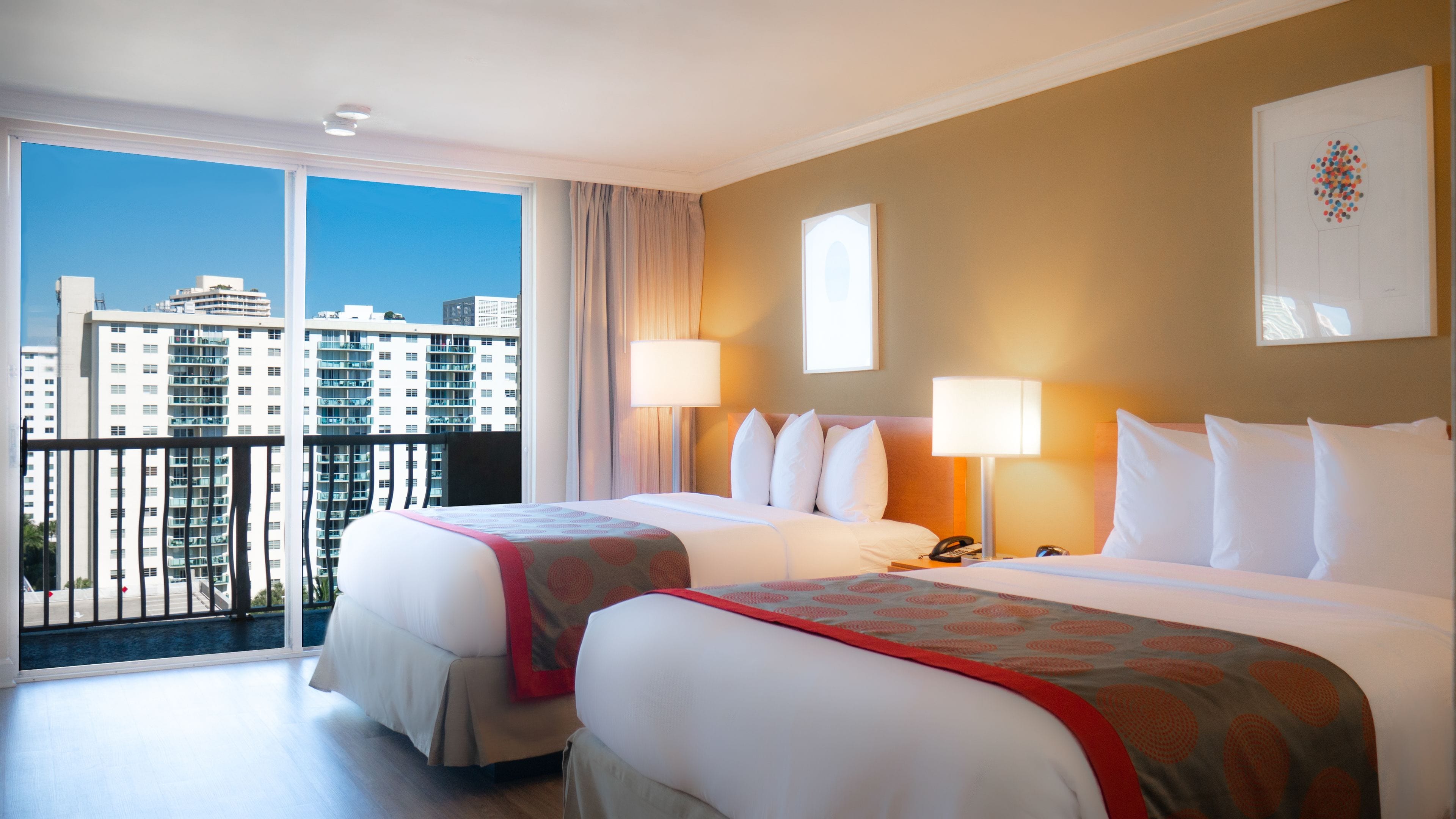 Une chambre d’hôtel avec deux lits, un balcon et une vue sur la ville.