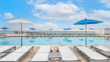 Alberca al aire libre, sombrillas en la alberca y camastros