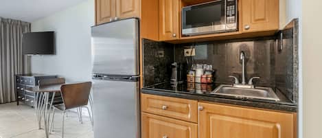 Una cocina moderna con armarios de madera, un refrigerador de acero inoxidable, un microondas y un lavamanos.