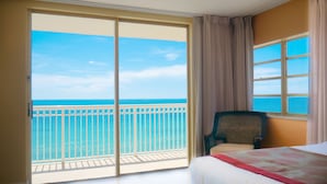 Una camera d'albergo con un'ampia porta-finestra scorrevole che si apre su un balcone con vista sull'oceano.