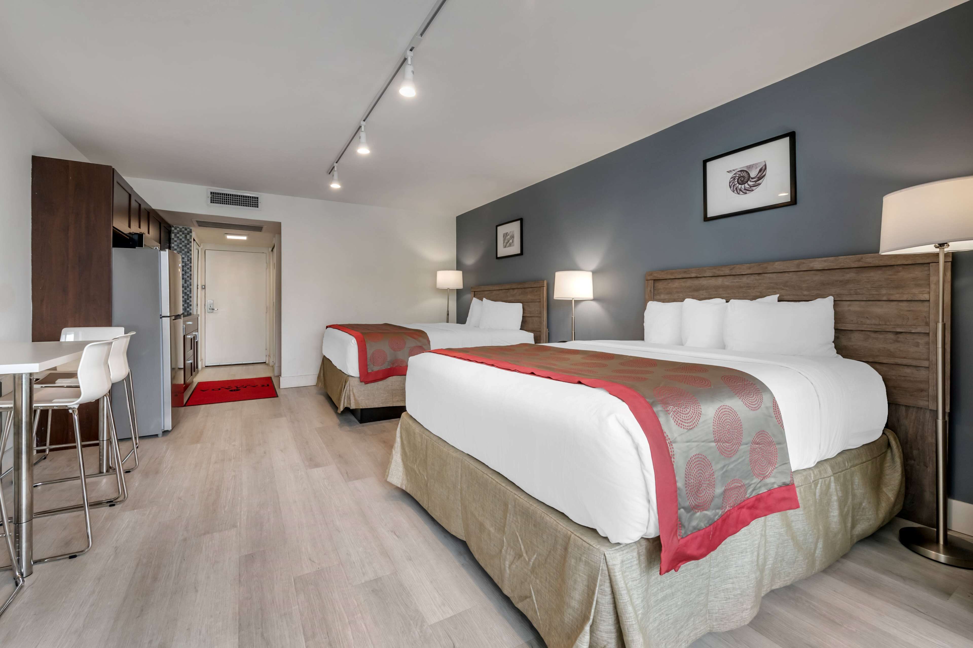 A hotel room with two beds, a dining area, and a kitchenette.