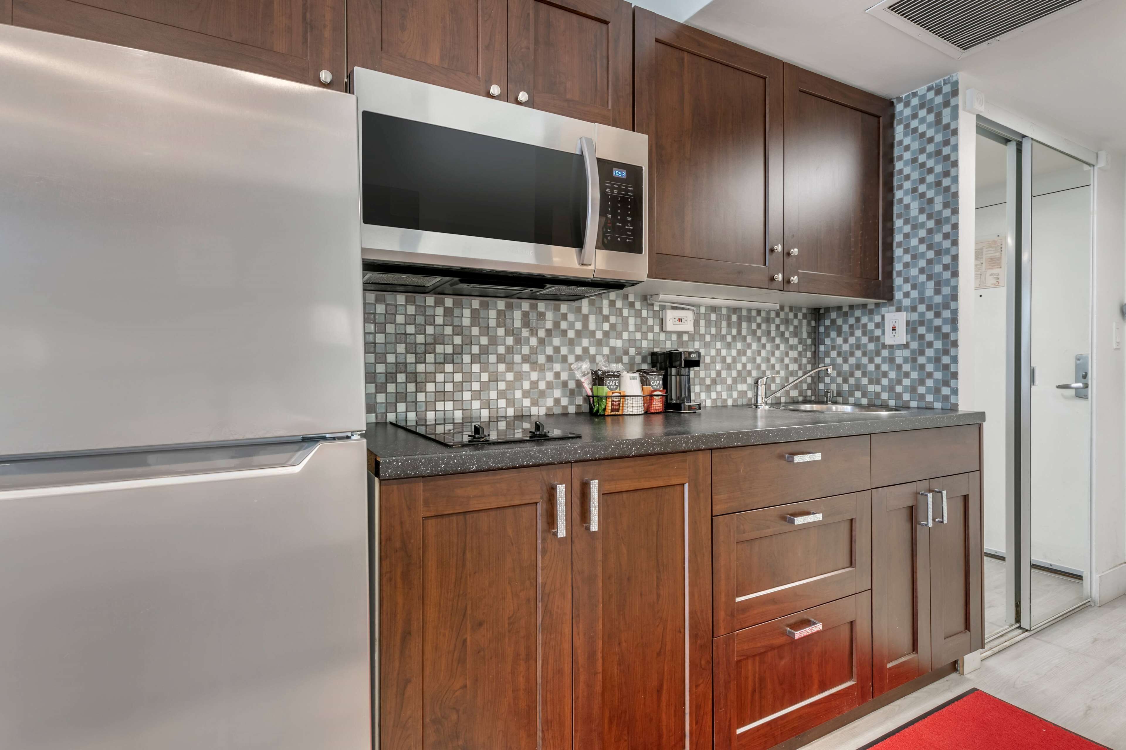A modern kitchen with stainless steel appliances, wooden cabinets, and a tiled backsplash.