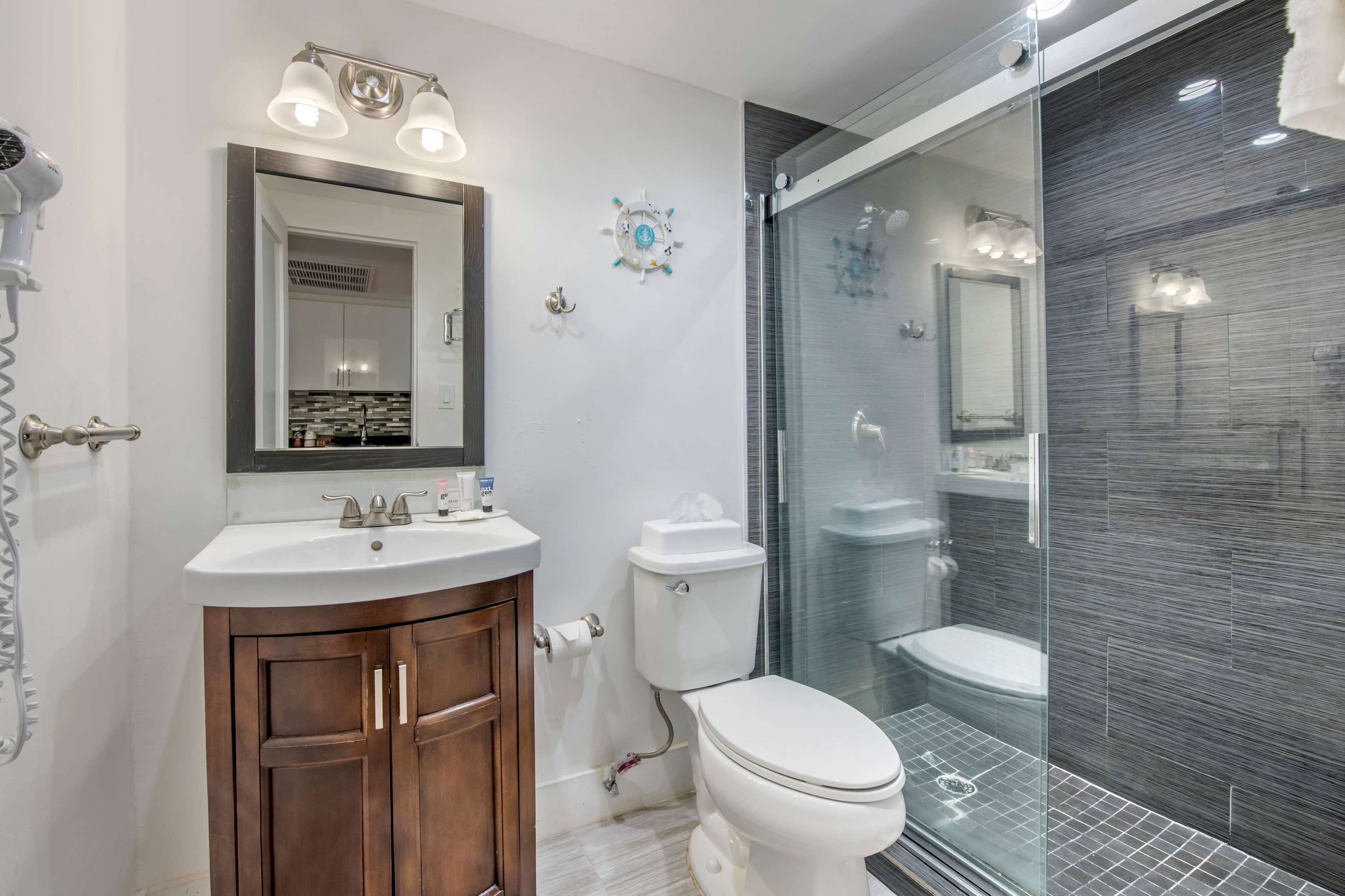 A modern bathroom with a vanity, toilet, and glass shower enclosure.