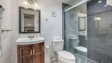 A modern bathroom with a vanity, toilet, and glass shower enclosure.
