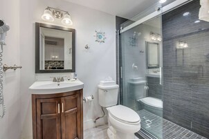 A modern bathroom with a vanity, toilet, and glass shower enclosure.