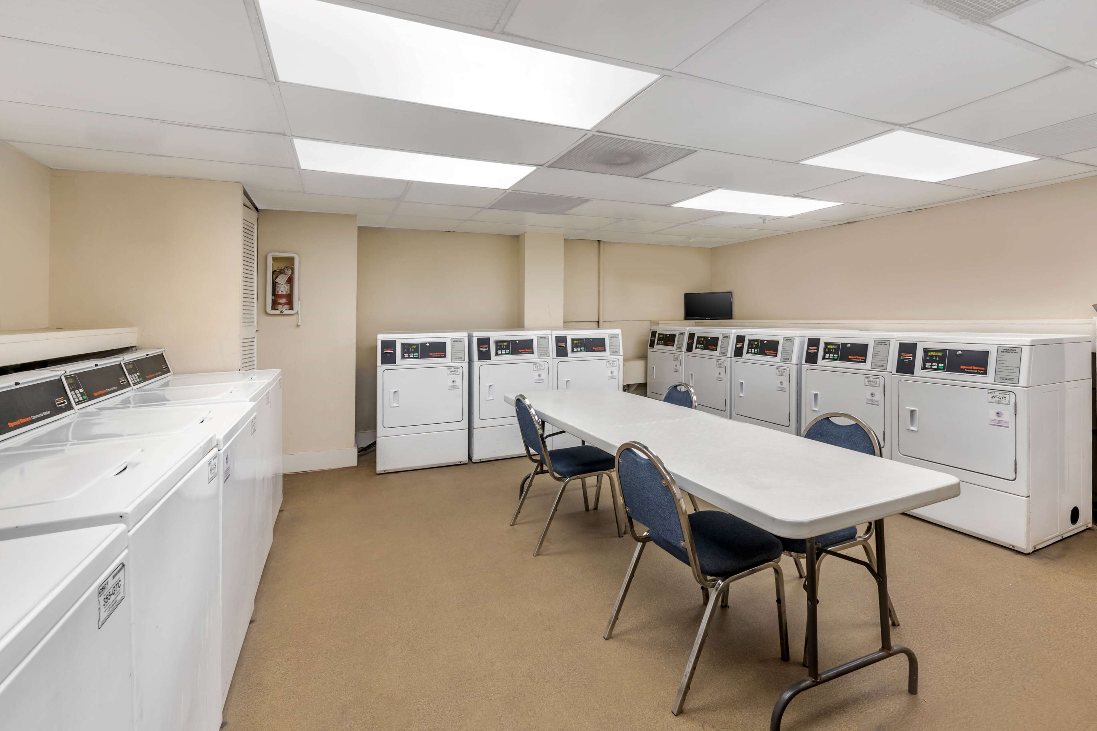 A clinical room with a long table and chairs, several medical machines, and a television on the wall.
