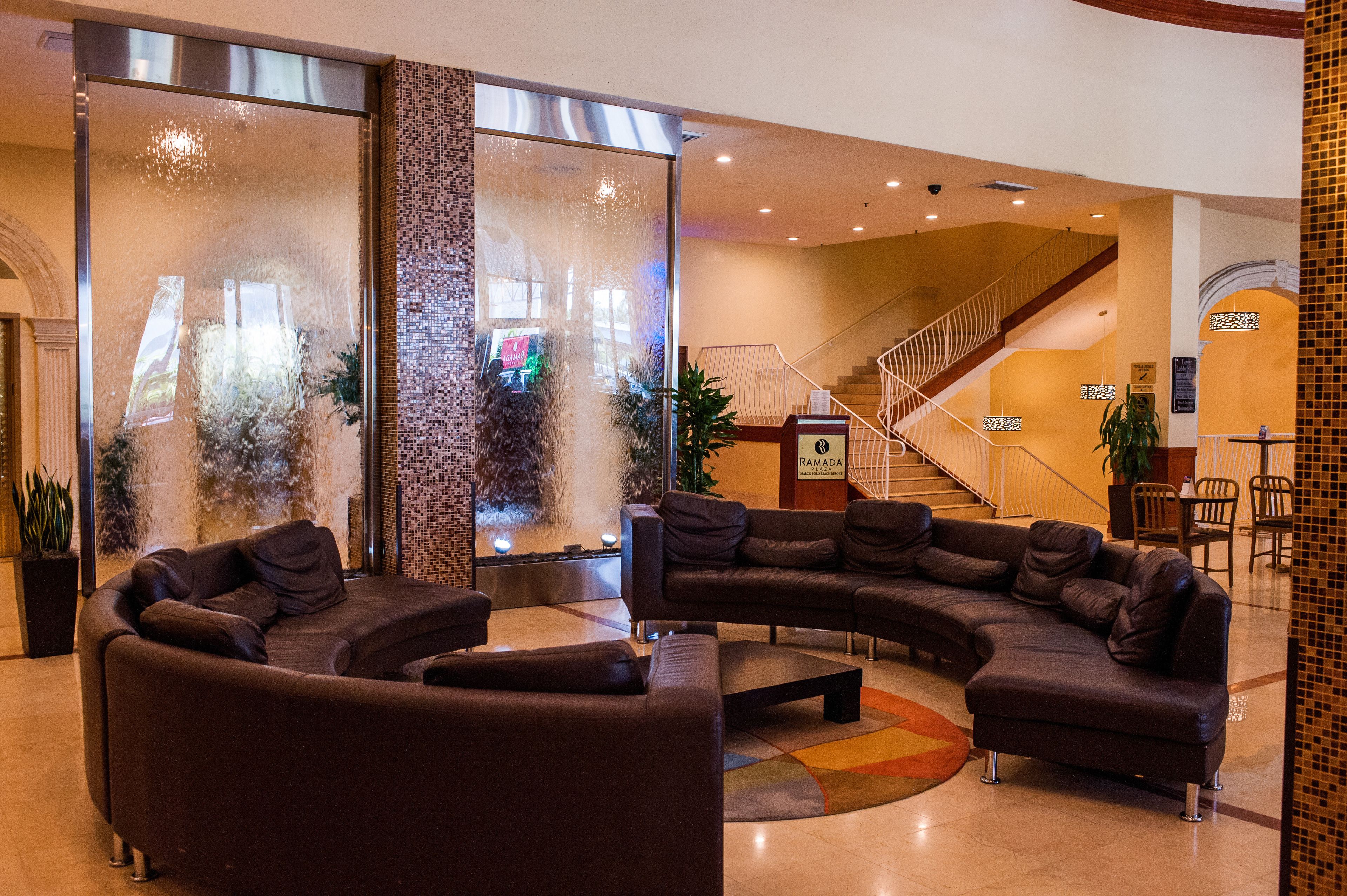 A lobby with a curved sectional sofa, a fountain, and a staircase.