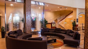A lobby with a curved sectional sofa, a fountain, and a staircase.