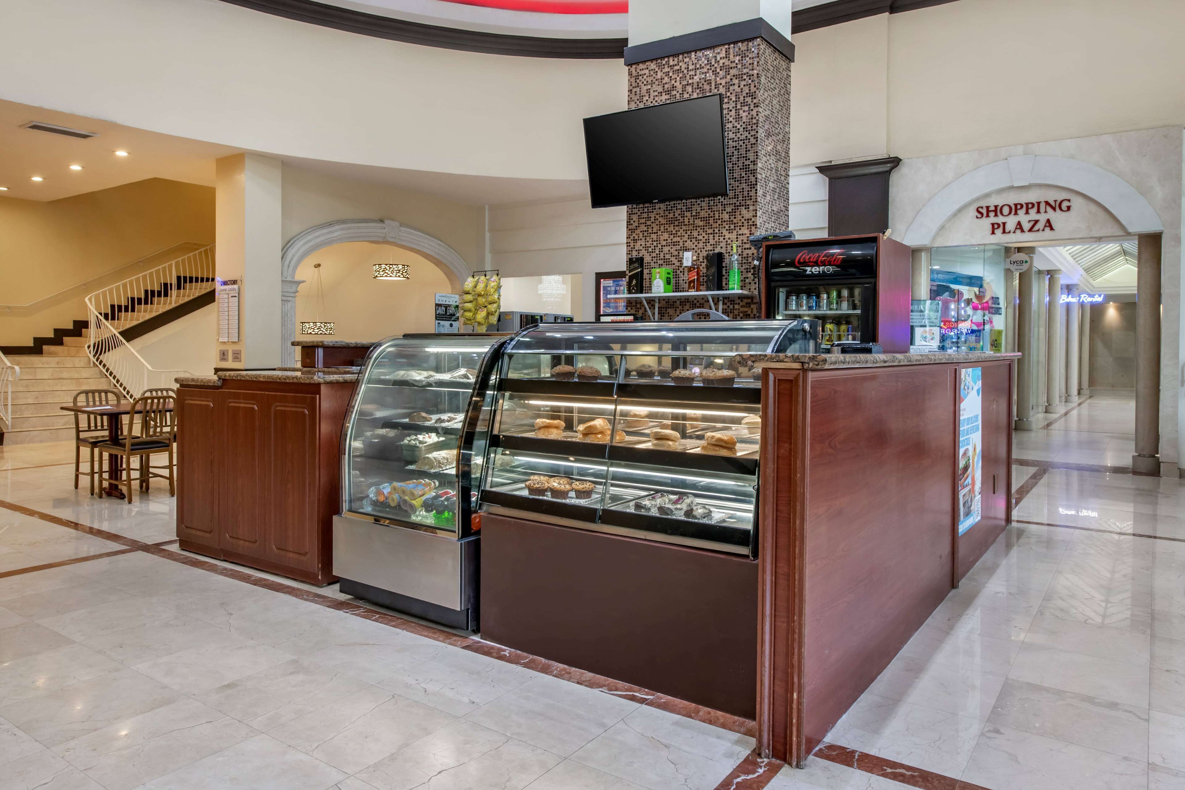 Een bakkerijtoonbank met gebak, een trap en een bord met 'Shopping Plaza'.