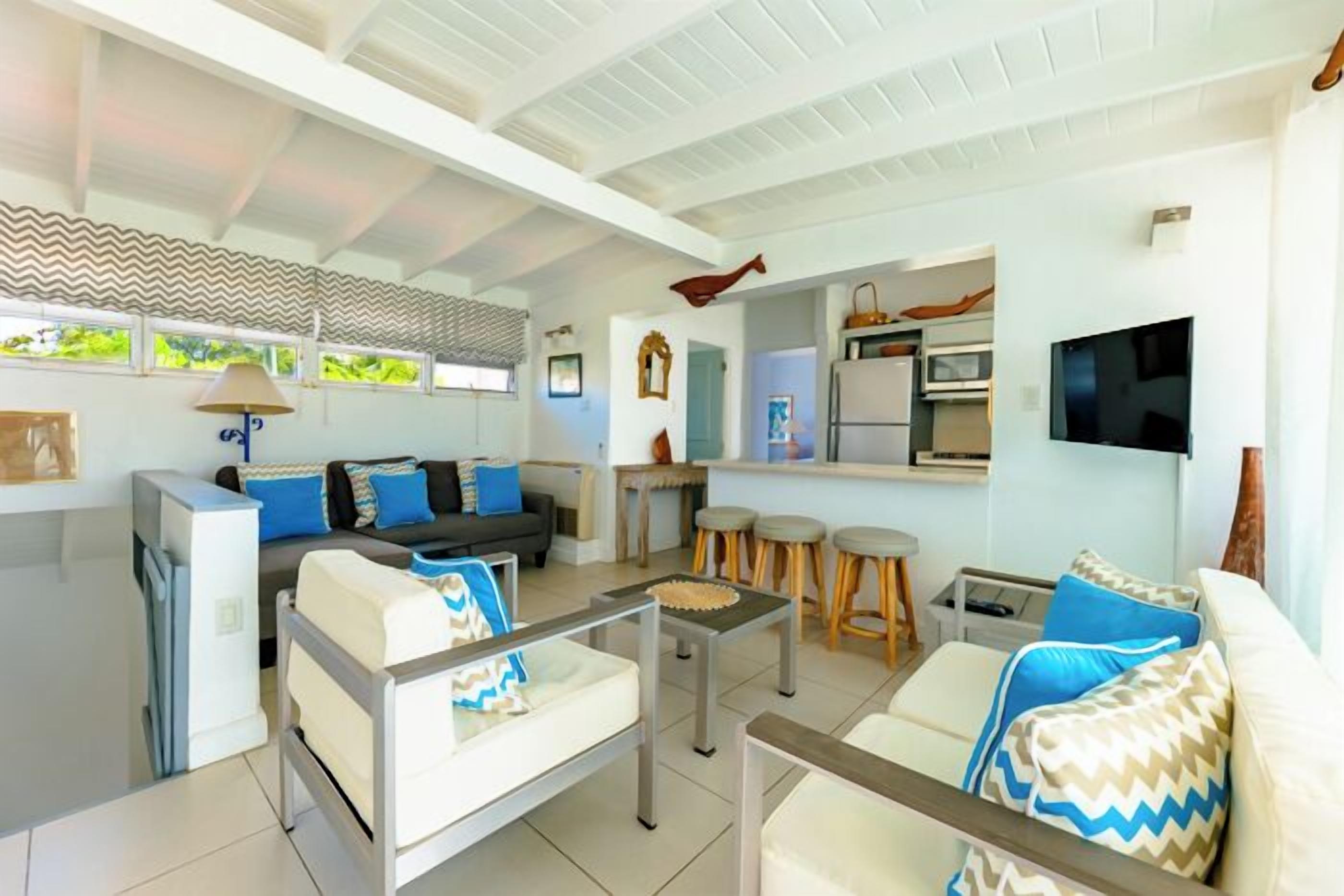 A modern living room with a sofa, coffee table, and kitchen area visible.