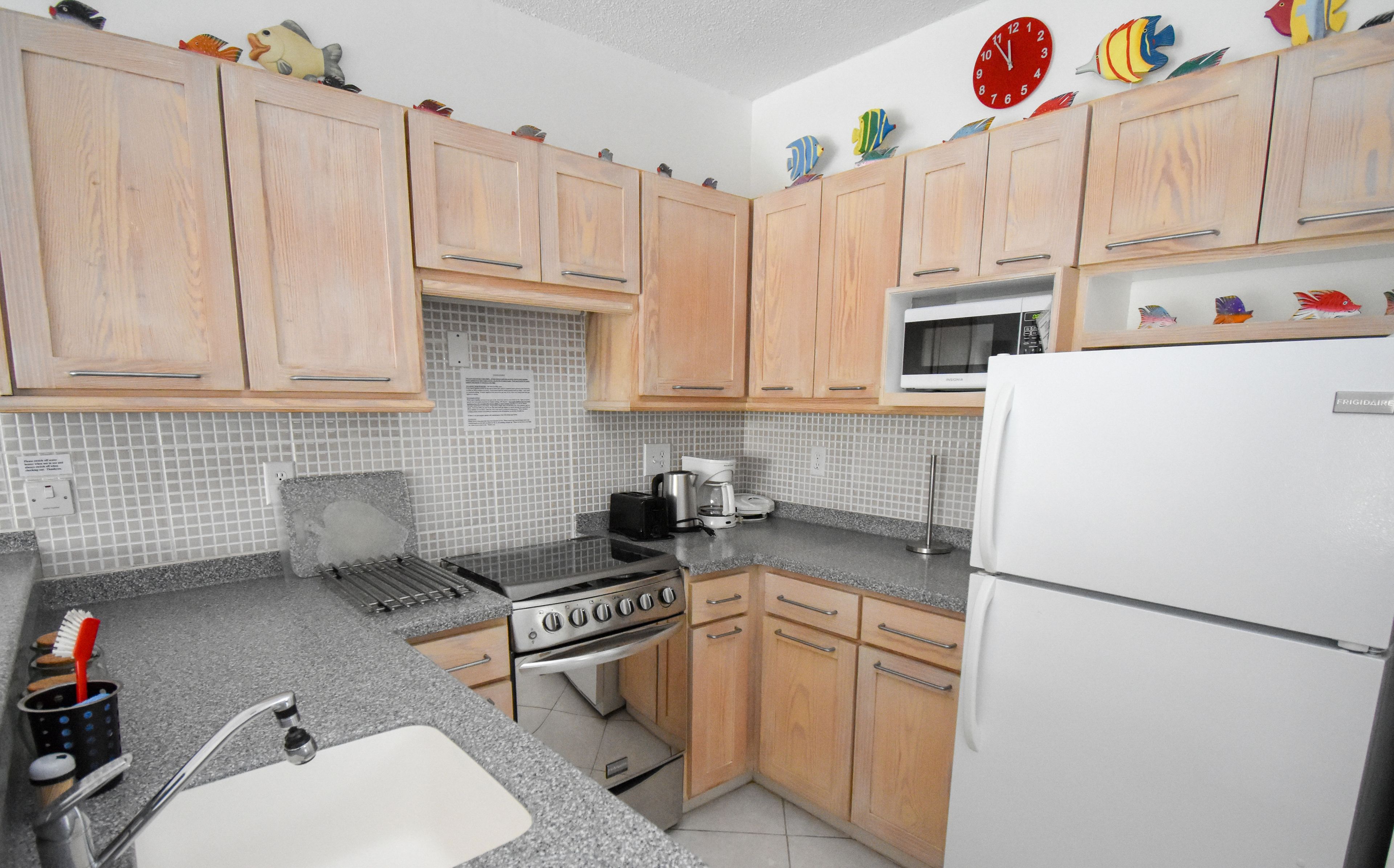 A kitchen with wooden cabinets, a microwave, a stove, and a sink.