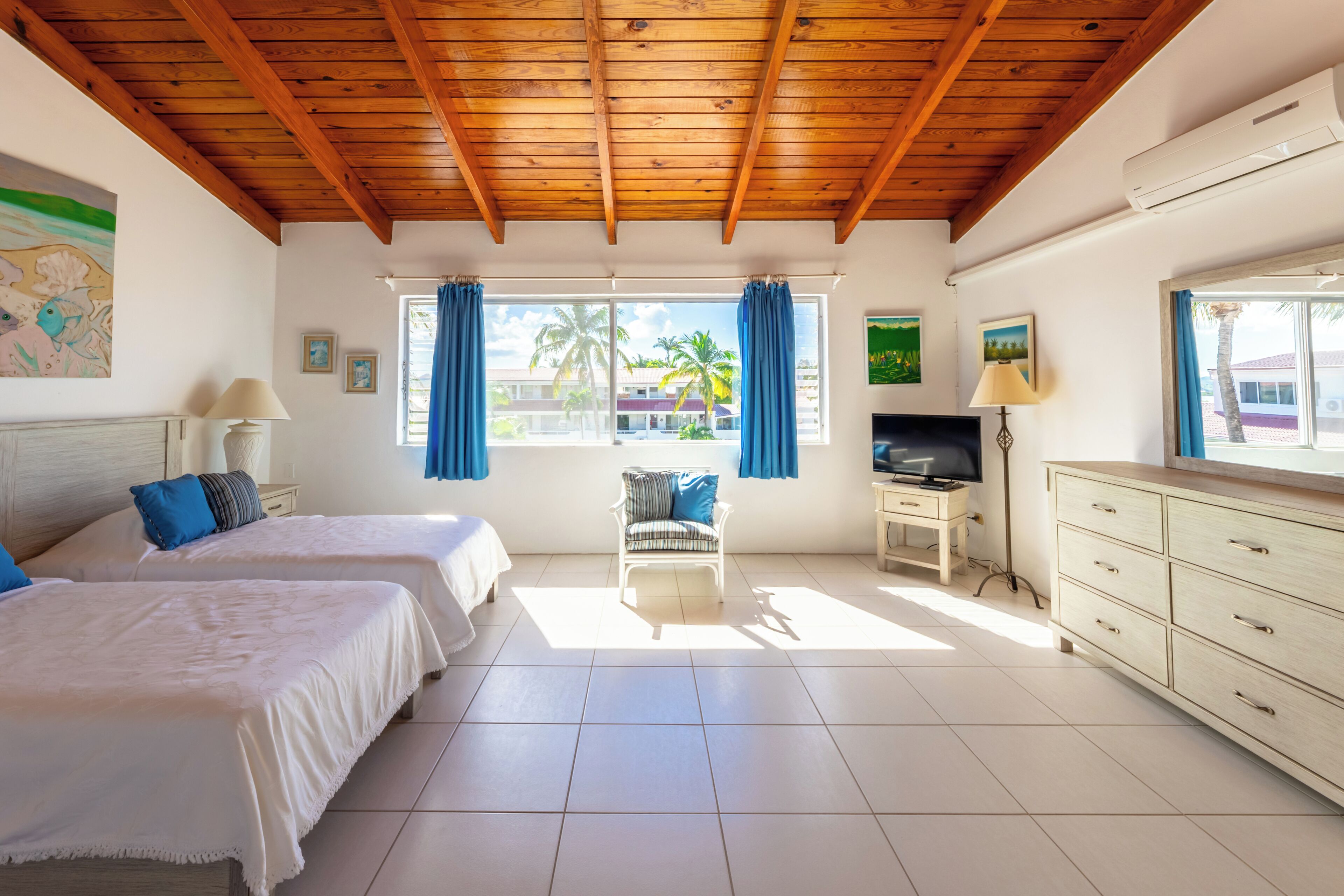 Une chambre avec deux lits, une télévision, un bureau et une chaise.