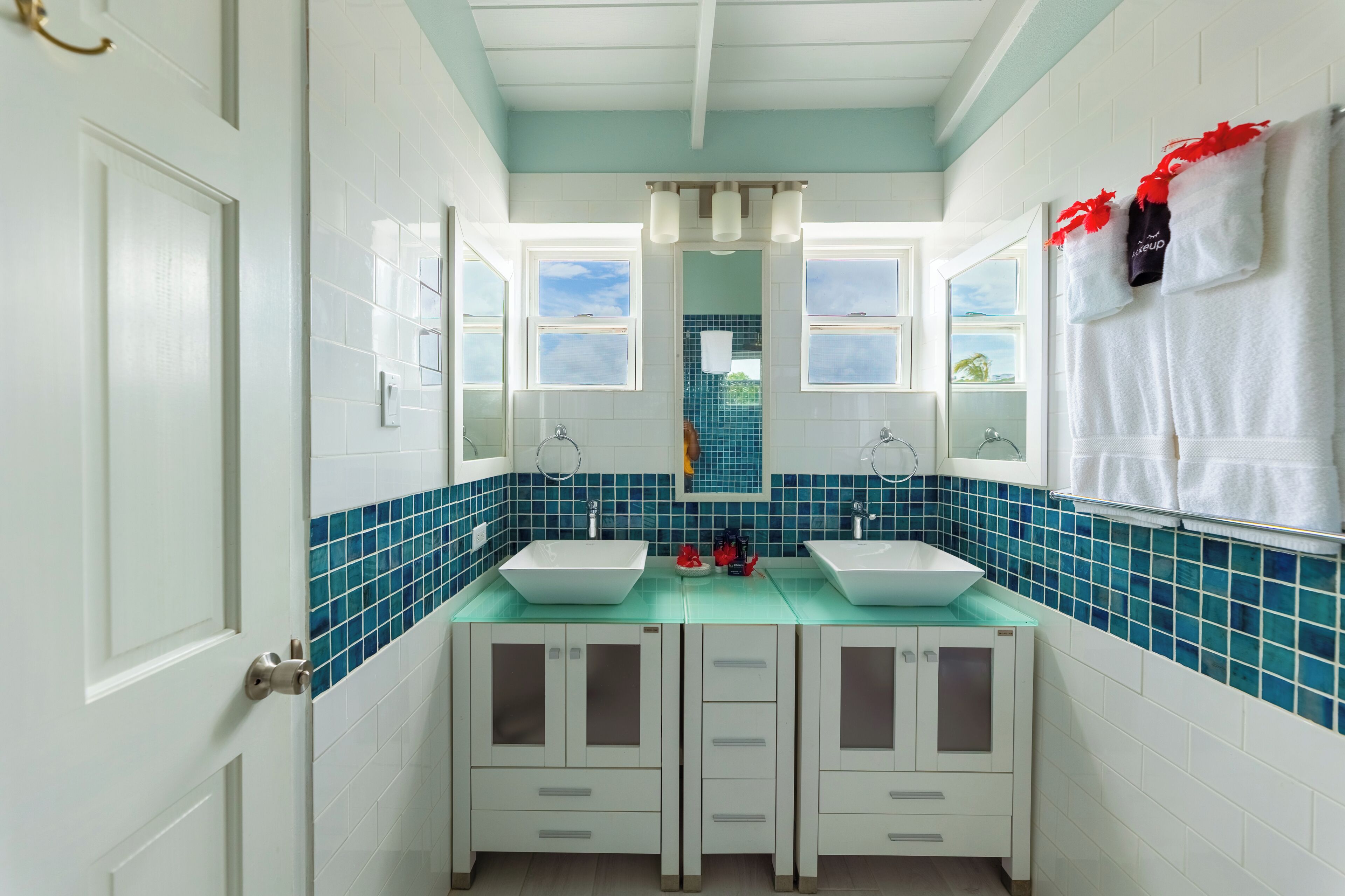 Un baño con dos lavamanos, un espejo y una ventana.