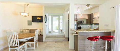 A modern kitchen with a dining area, a bar, and a seating area with a view.