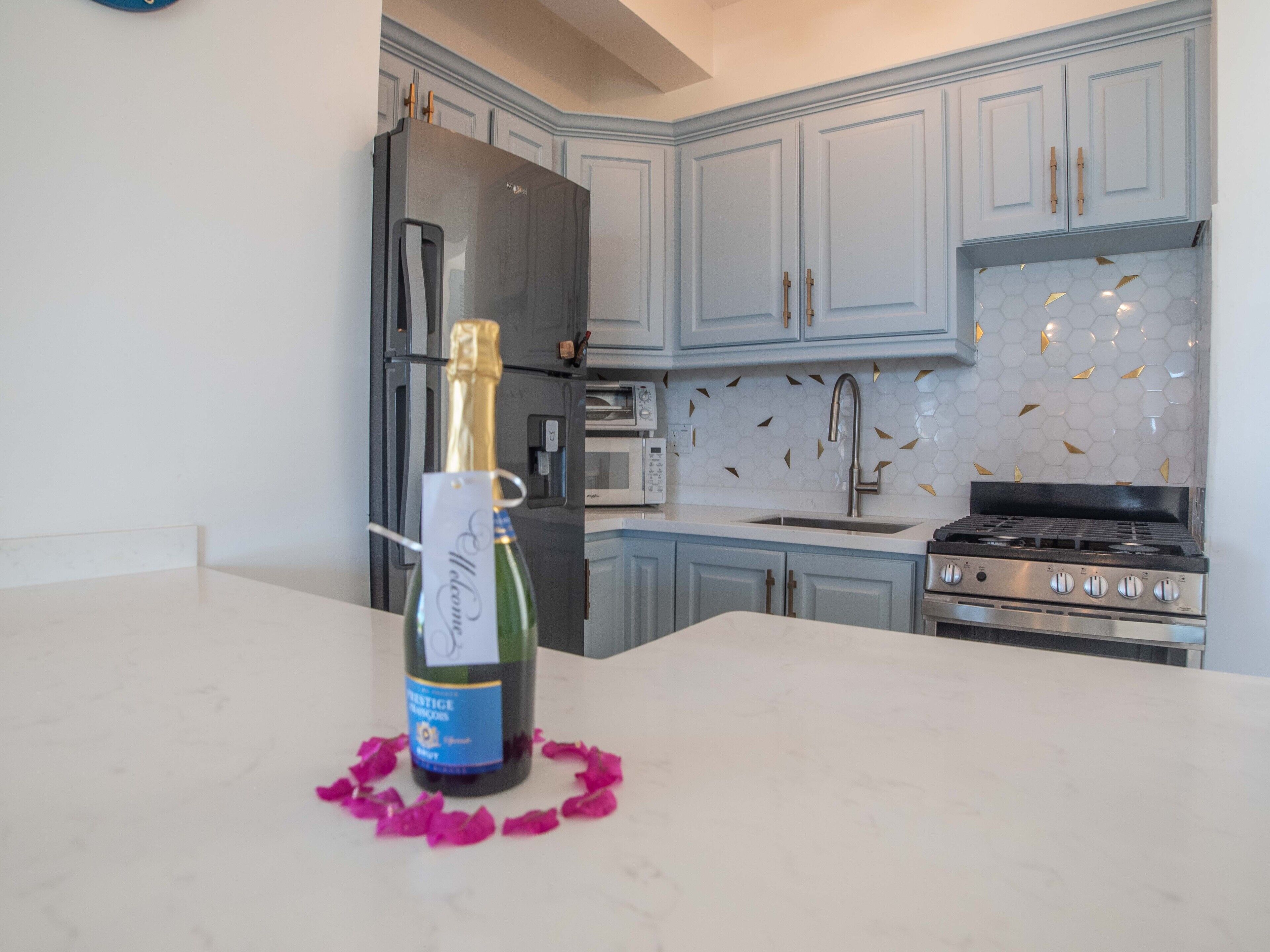 A kitchen with light blue cabinets, a stainless steel refrigerator, a gas stove, and a microwave.