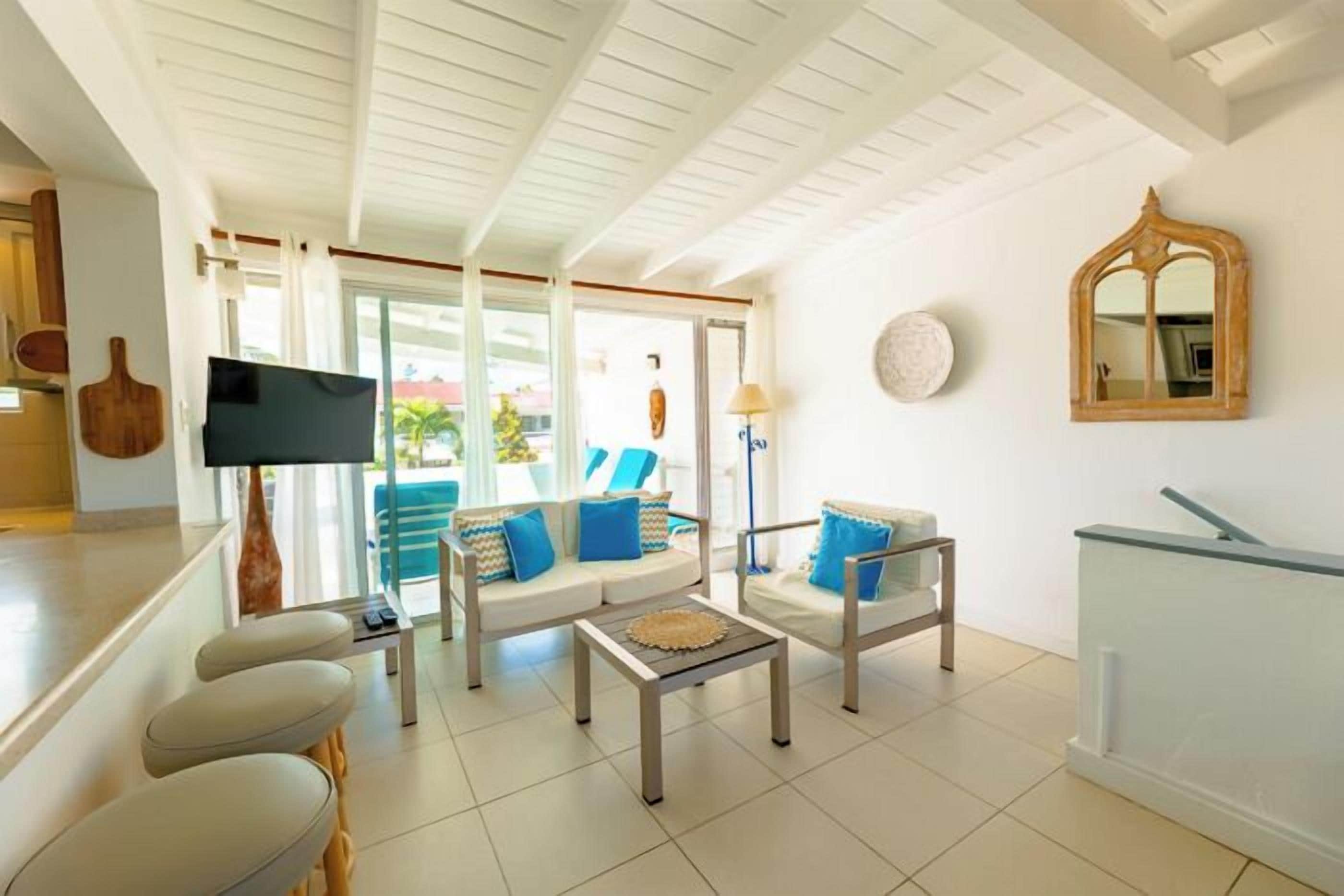 A spacious living area with a sofa, armchairs, a coffee table, and a television.